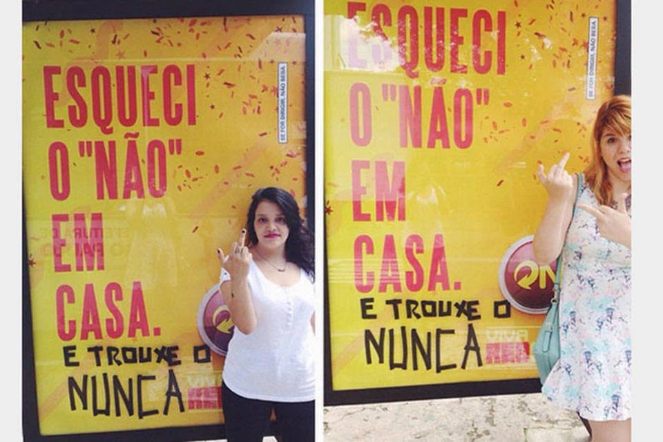 Women doing obscene gestures in front of a Skol advertising.